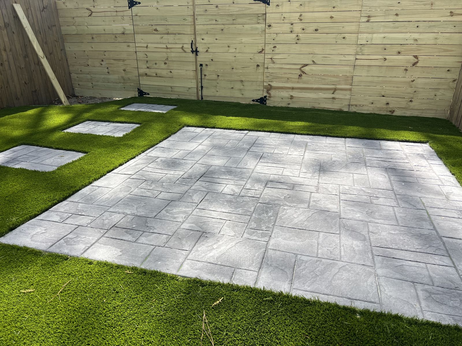 Stamped concrete backyard patio with paver-look pattern and inset stepping pads
