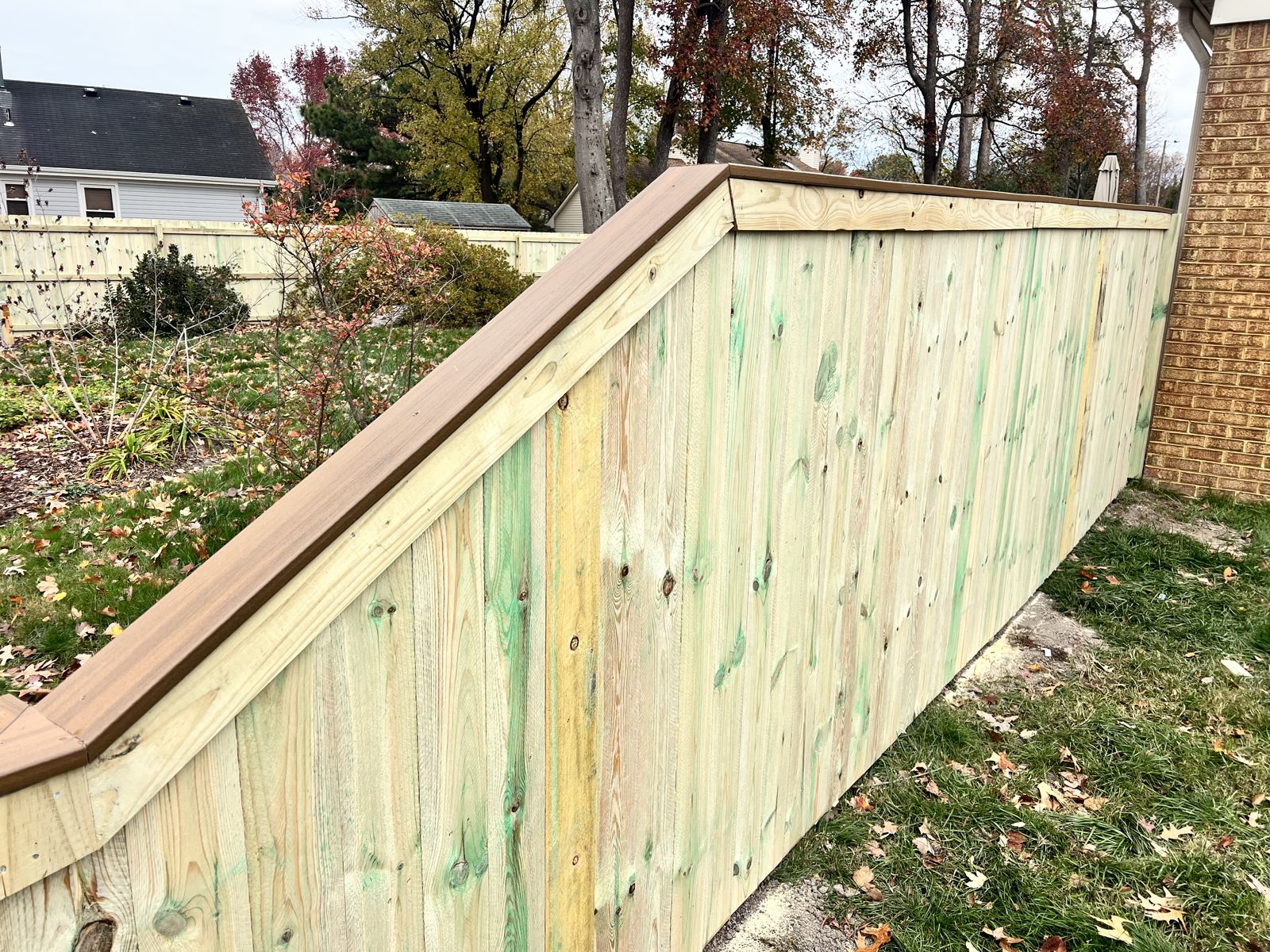 Wood fence stepped down a slope with composite cap rail